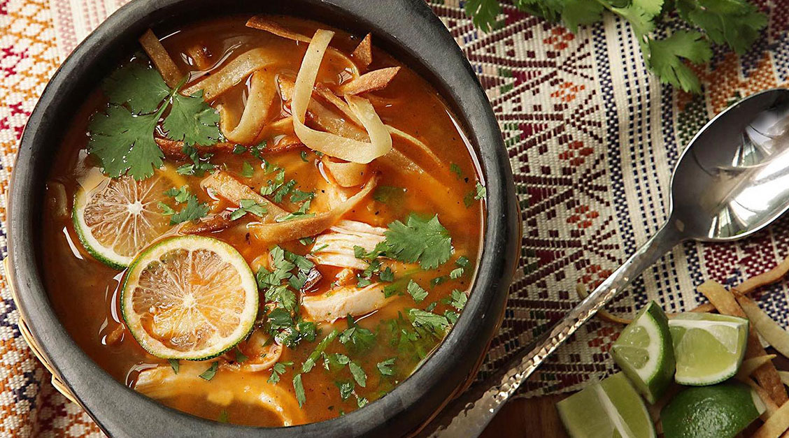 a bowl of soup with noodles and limes