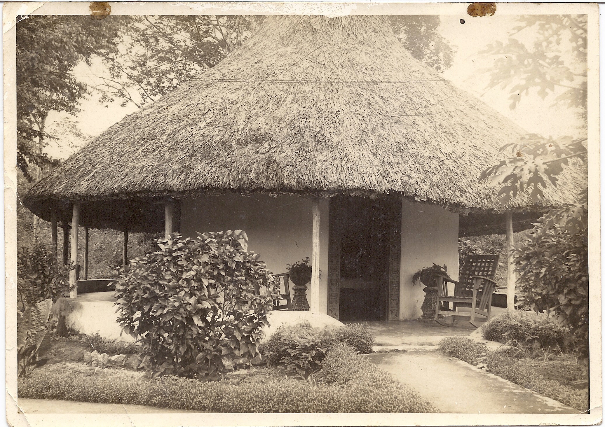 a thatched roof house with a chair and a bench