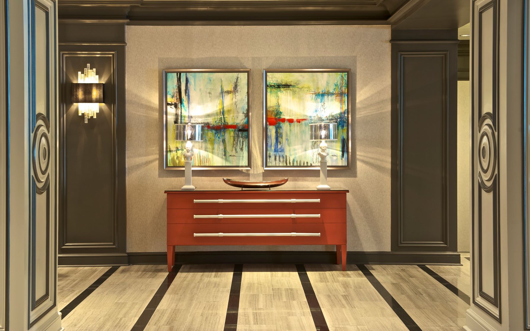 a room with a red dresser and two lamps
