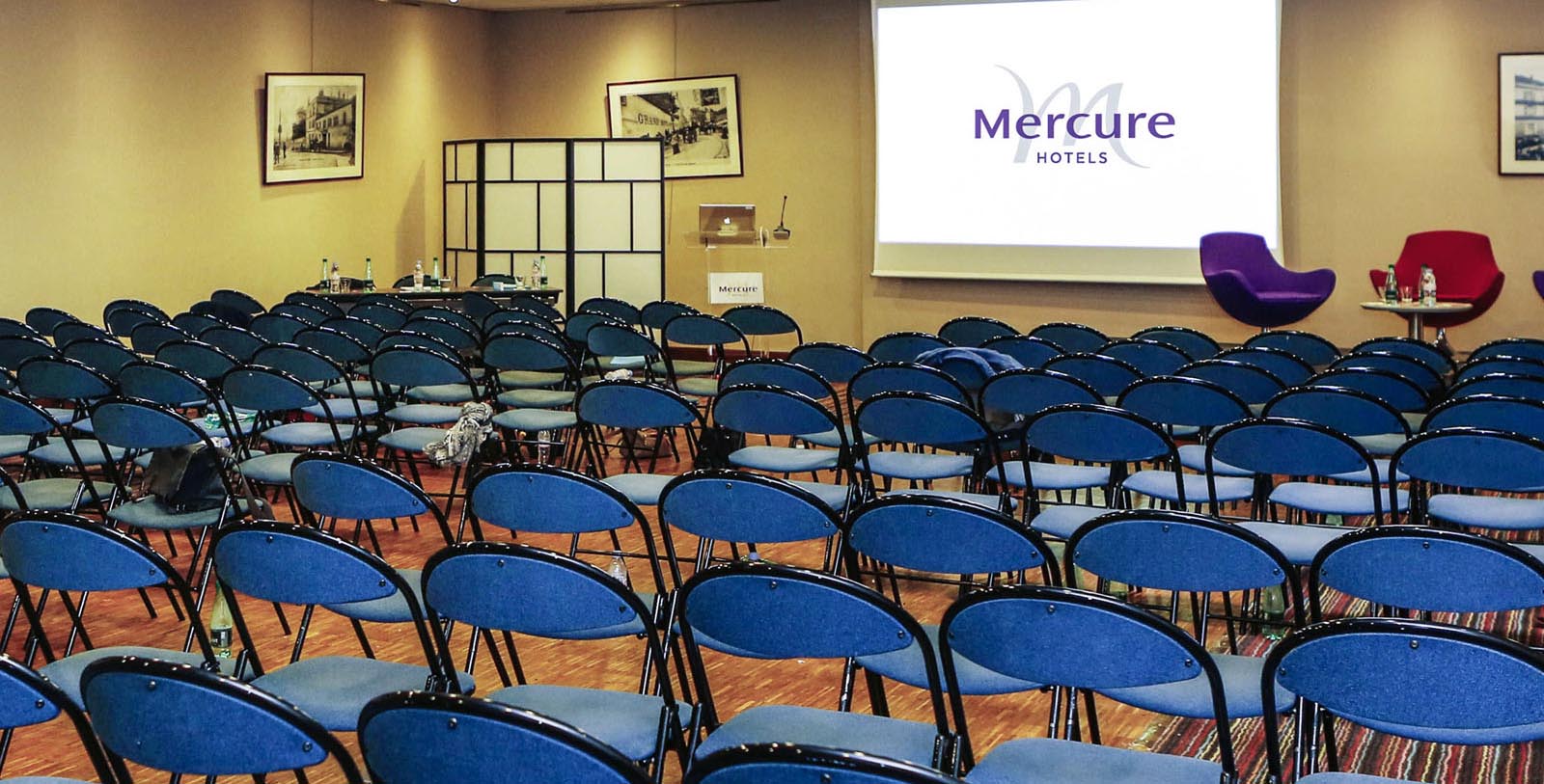 a room with blue chairs and a projector screen