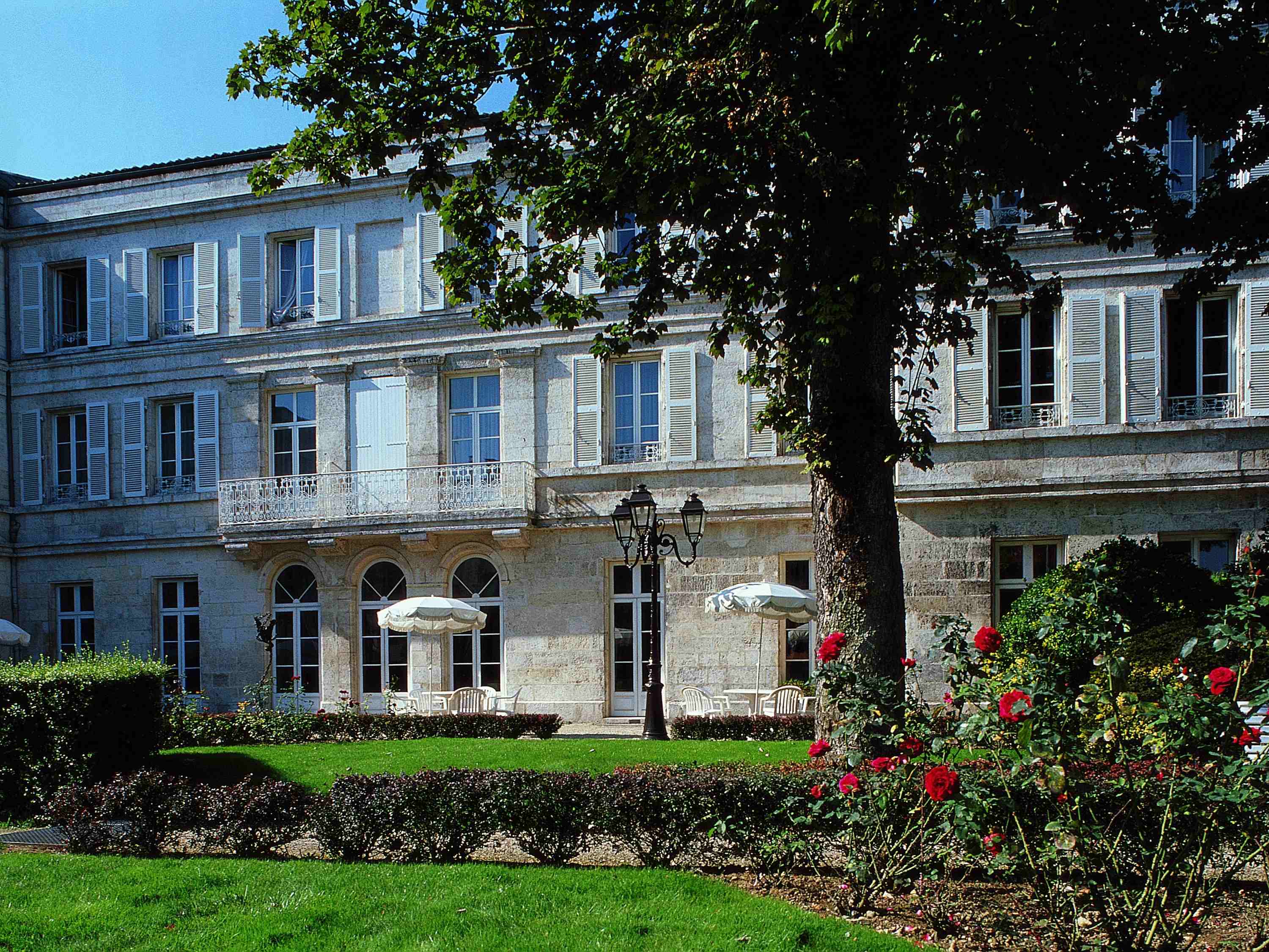 a large white building with a lawn and a tree