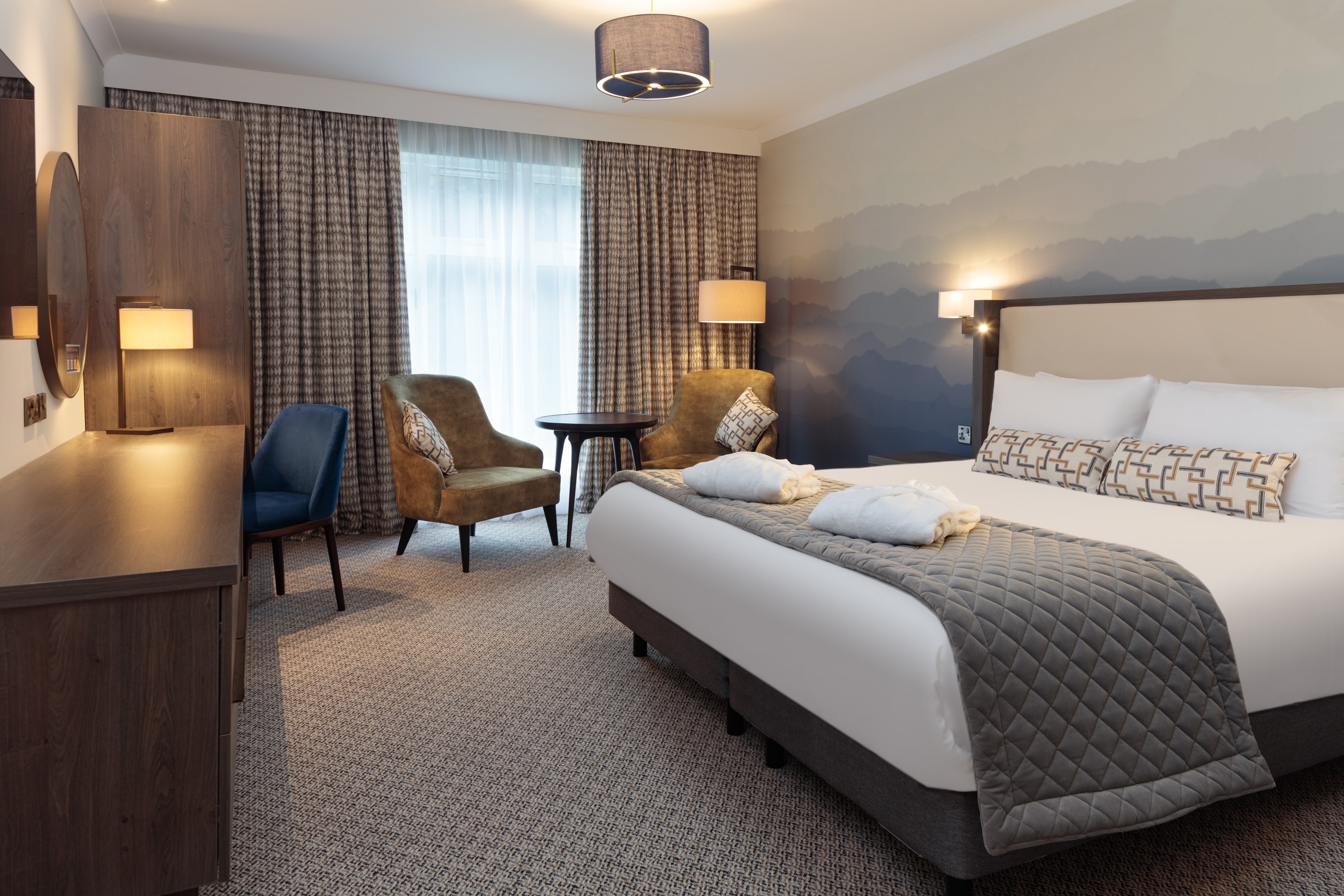 a room with a bed and chairs