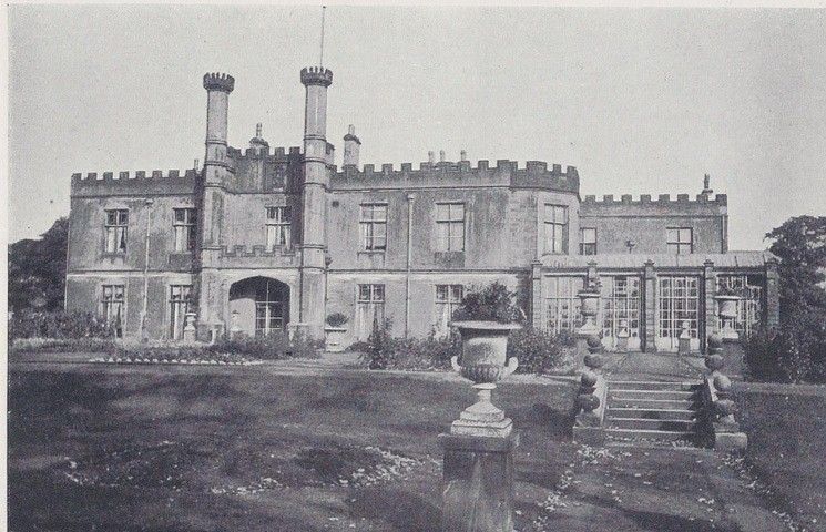 a large stone building with a lawn and a garden