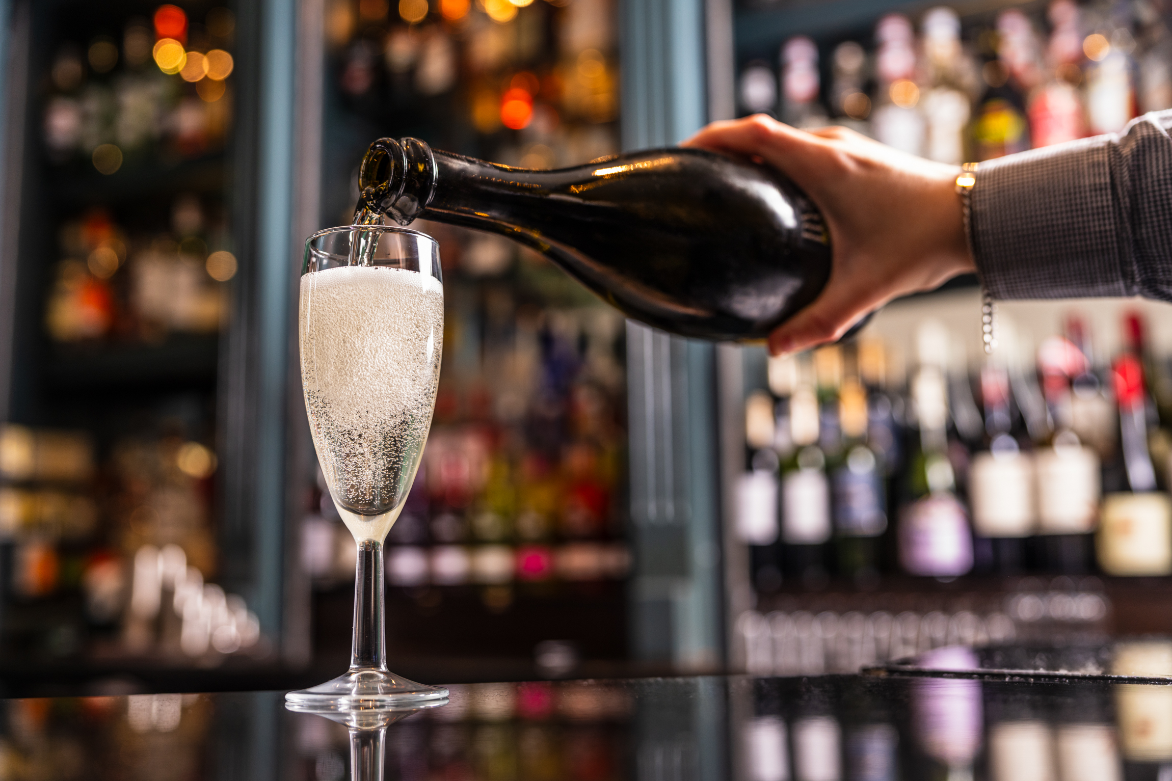 a person pouring a glass of champagne