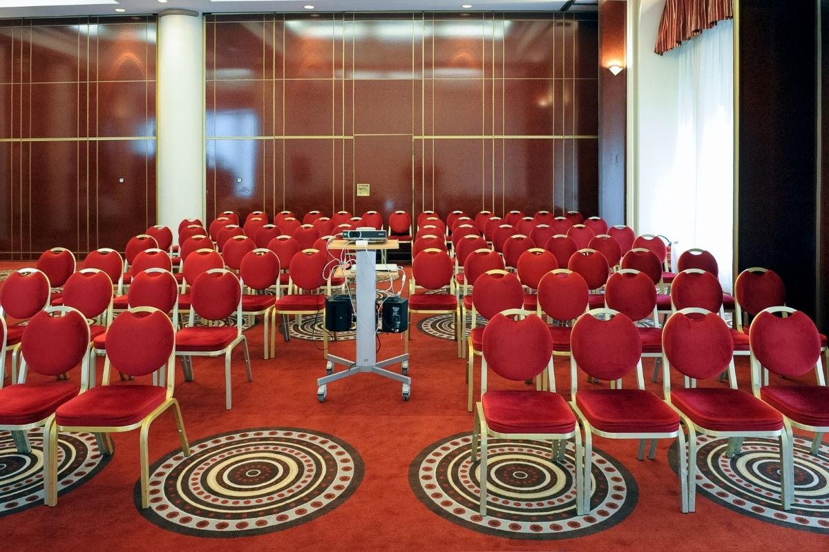a room with red chairs and a podium