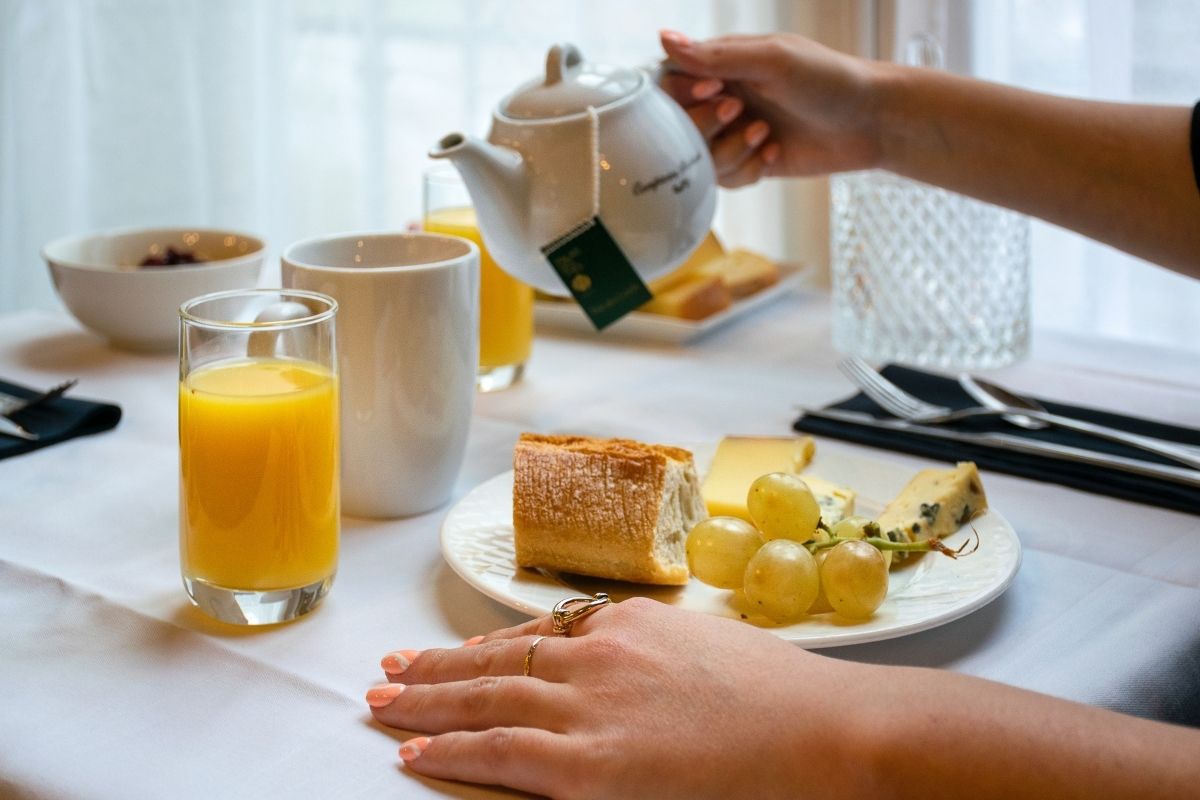 a hand pouring tea into a plate of food