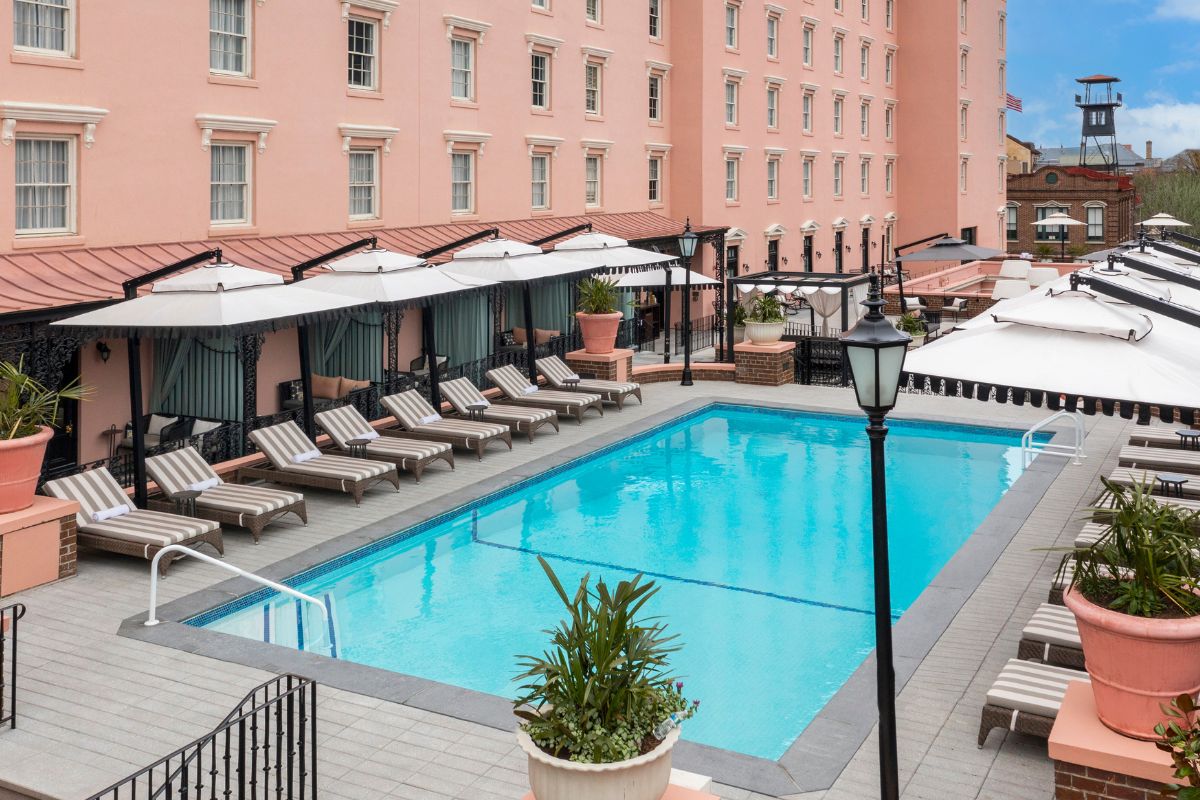 a pool with chairs and umbrellas in front of a building