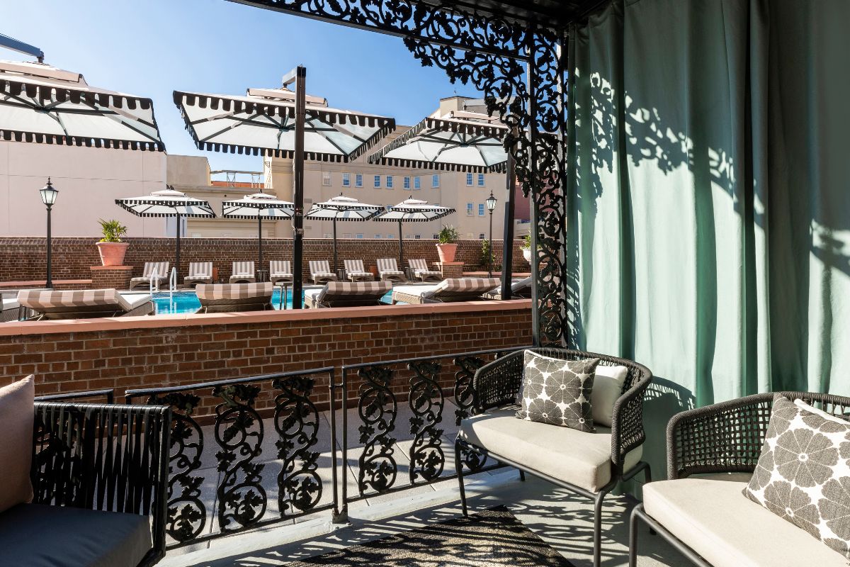 a patio with chairs and a pool in the background