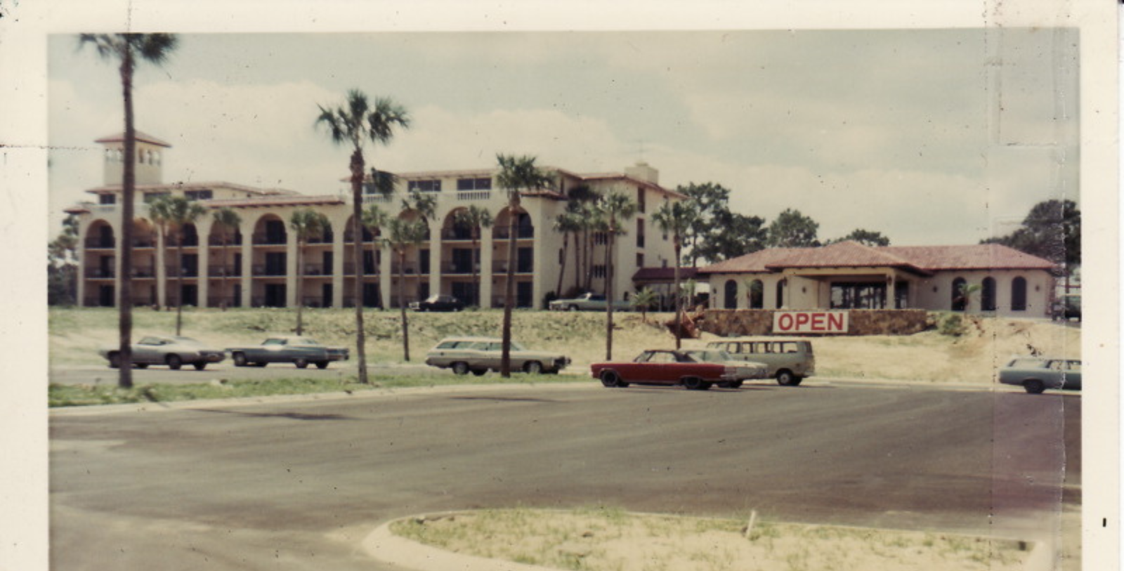 a building with palm trees and cars parked in front of it