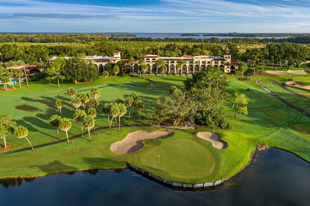 a golf course with a building and a body of water