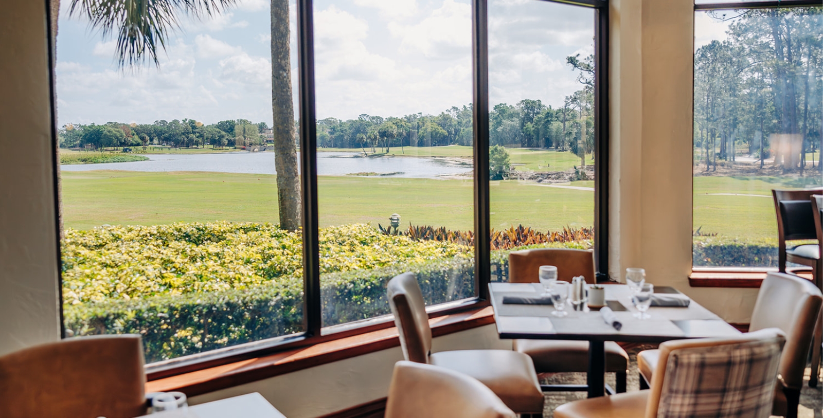 a table and chairs with a view of a golf course through a window