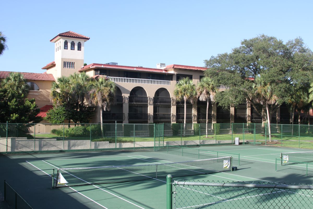 a tennis court with trees and a building