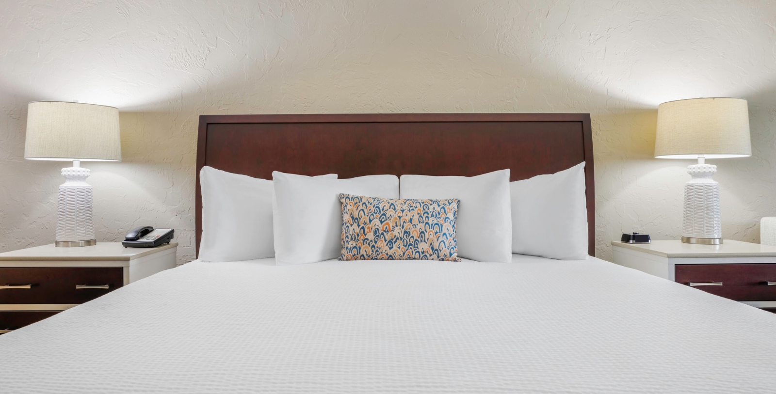 a bed with white pillows and a wooden headboard