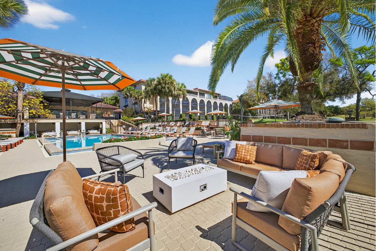 a patio with chairs and umbrellas and a pool