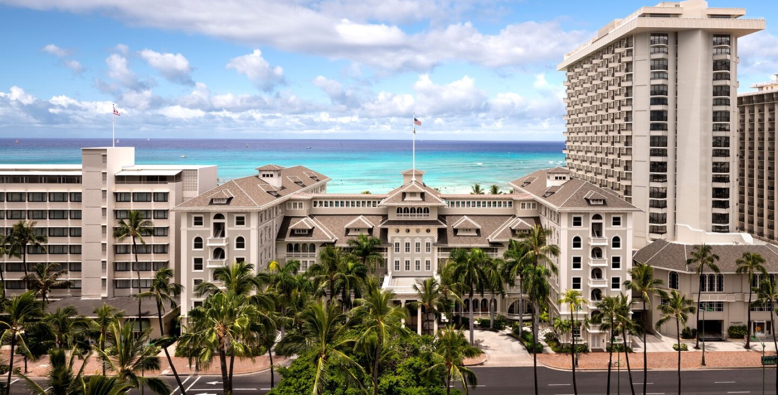 a large building with palm trees and a beach in the background