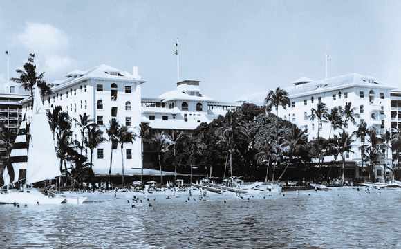 a large white building with many windows and a beach in the background