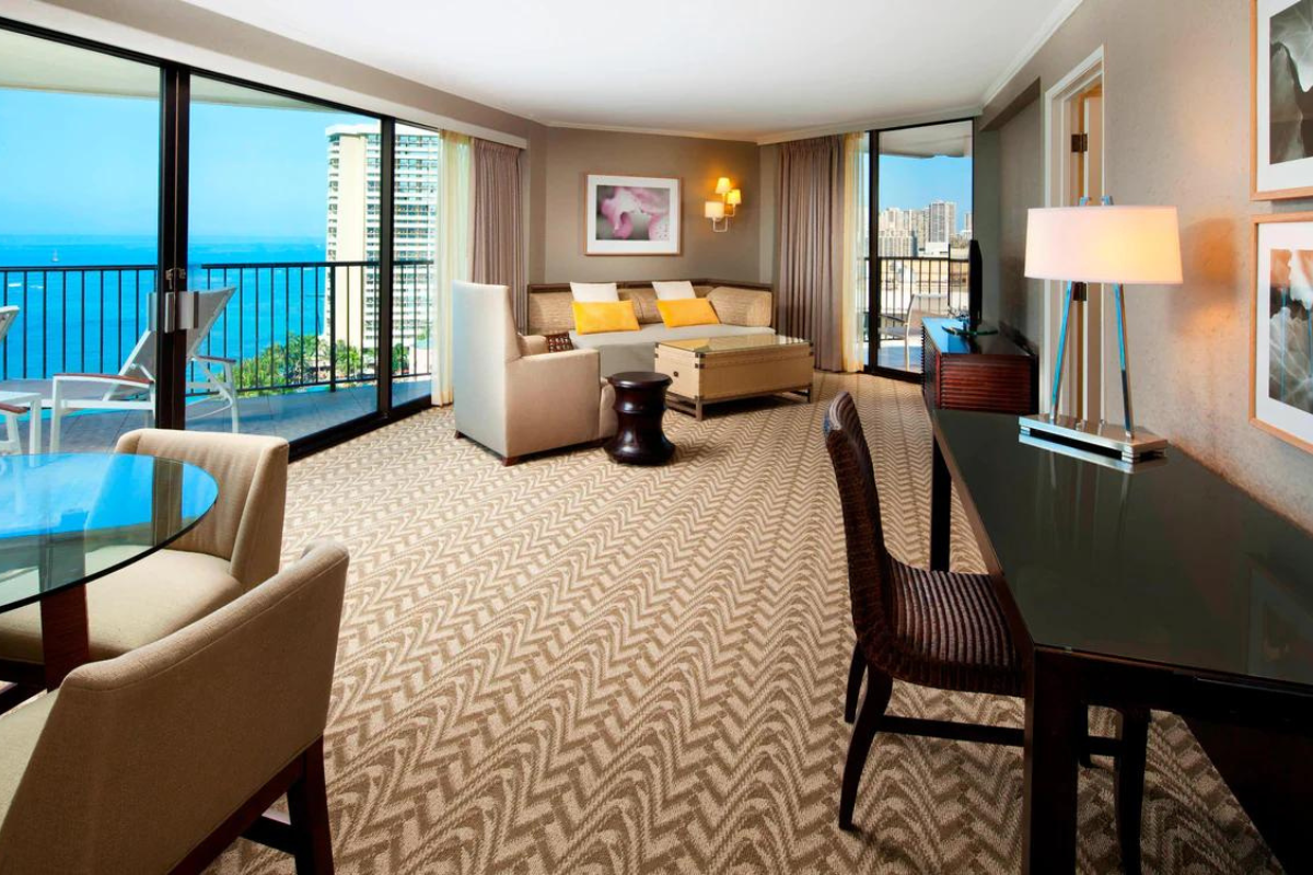 a room with a table and chairs and a balcony overlooking the ocean