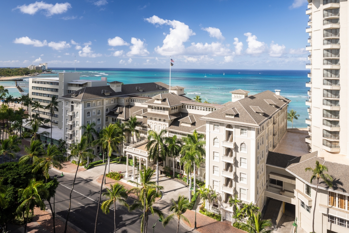 a building with palm trees and a beach in the background