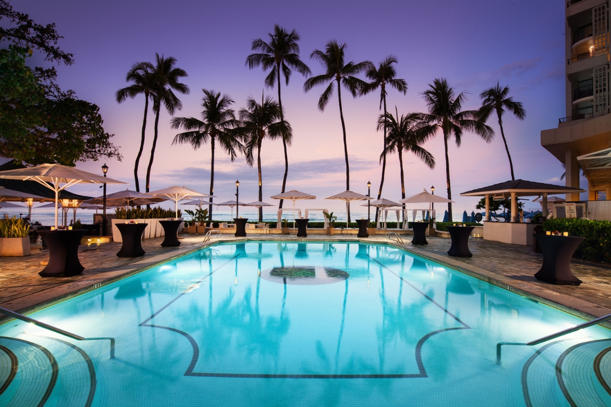 a pool with palm trees and umbrellas