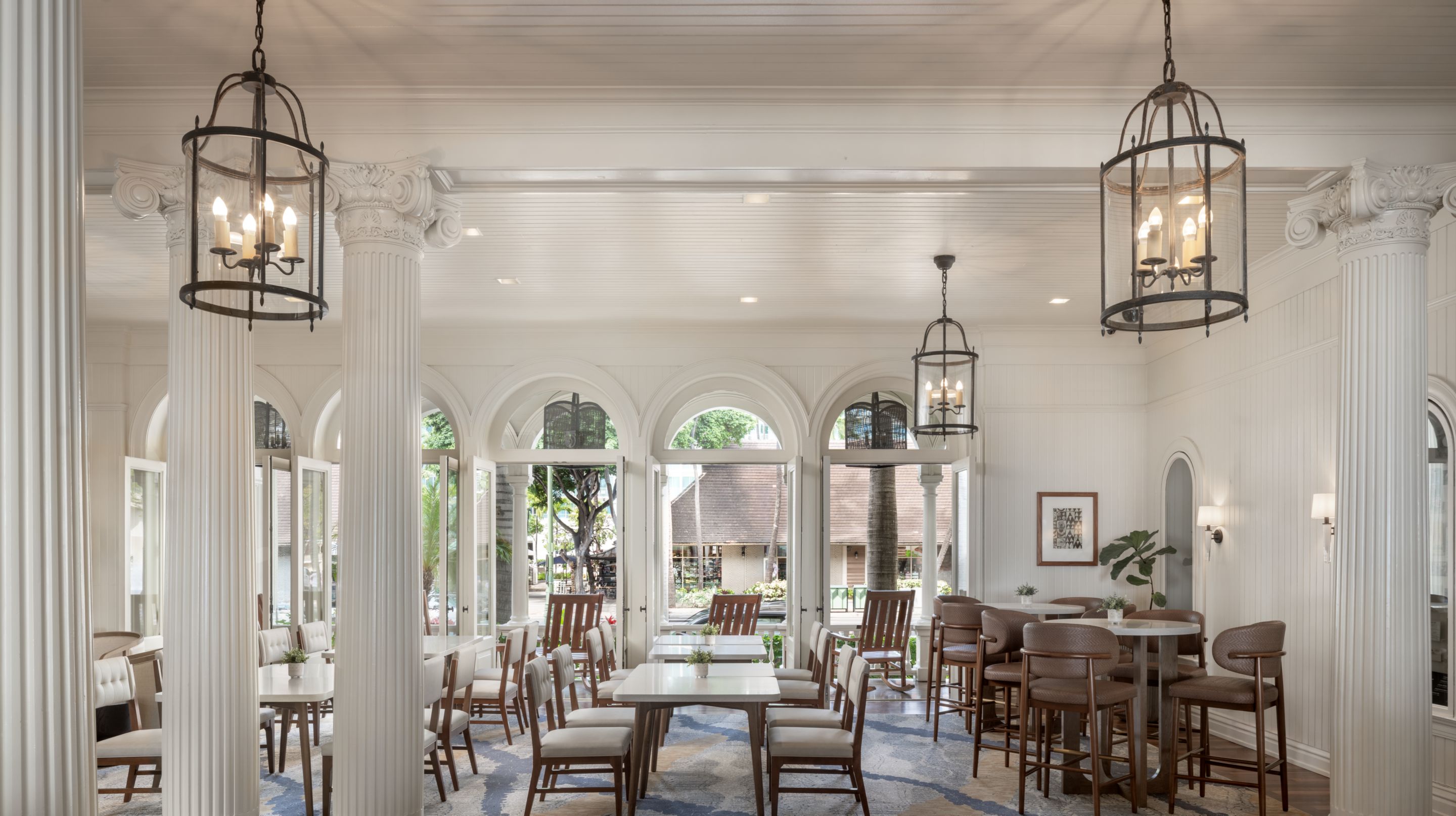a room with white columns and tables and chairs