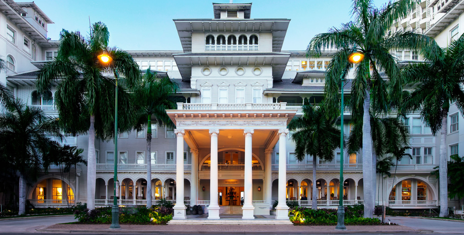a large white building with columns and palm trees