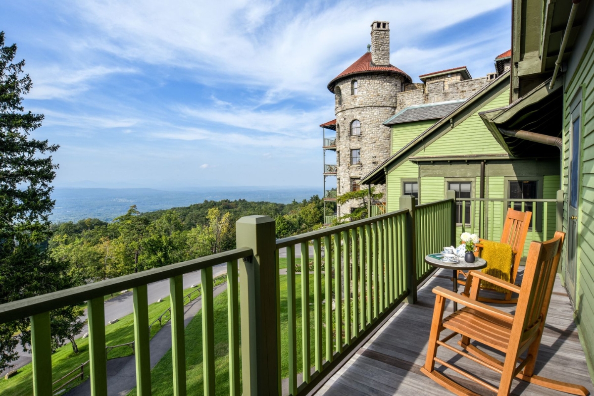 a deck with a table and chairs on it and a stone building in the background