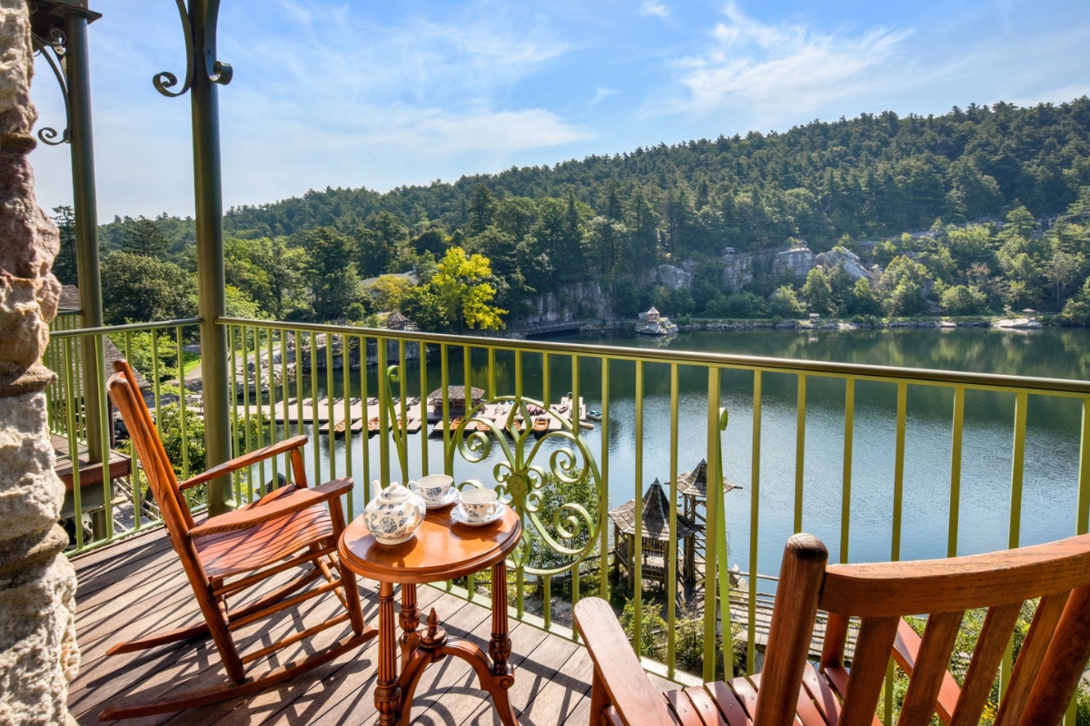 a table and chairs on a balcony overlooking a lake