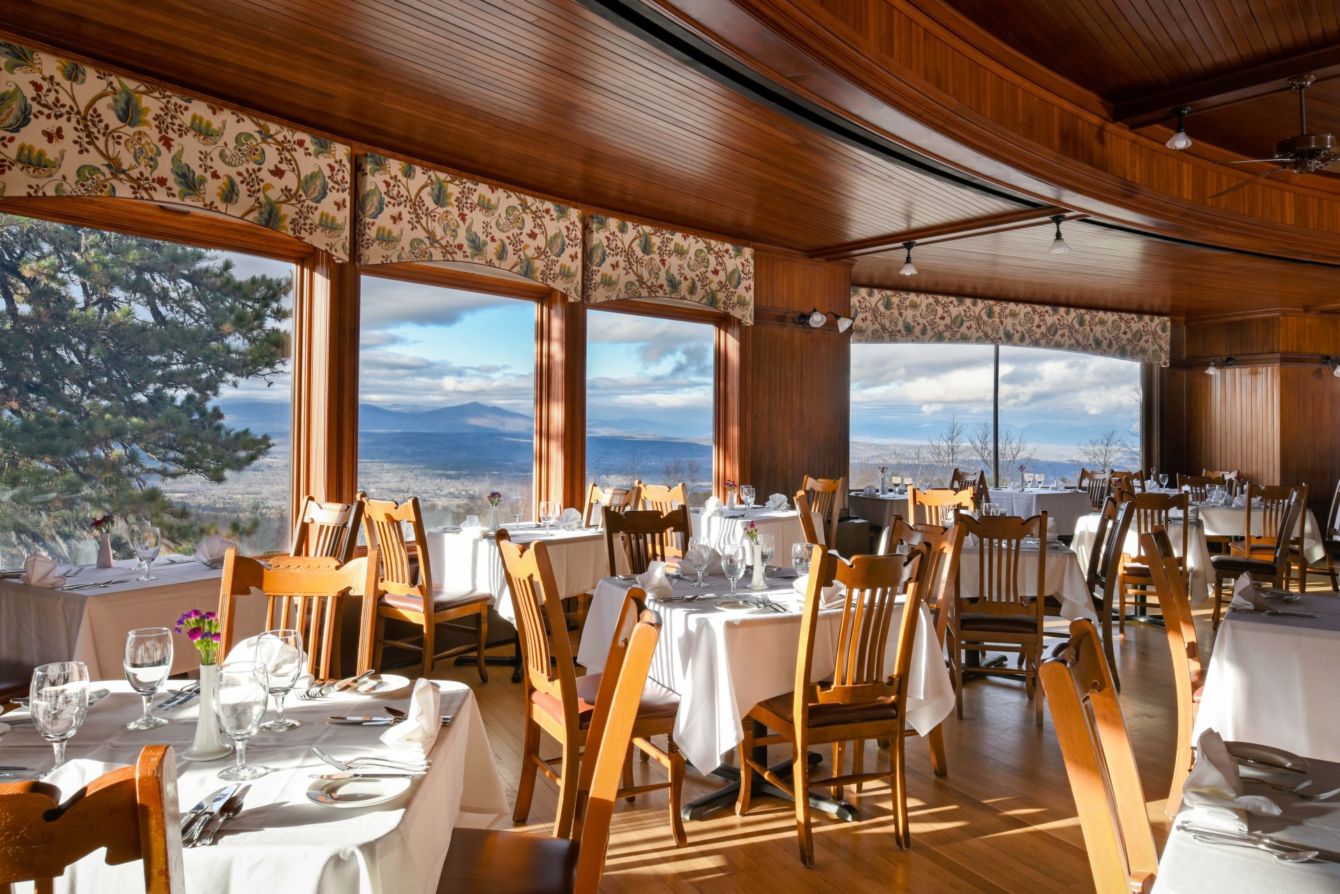 a room with tables and chairs and a view of mountains