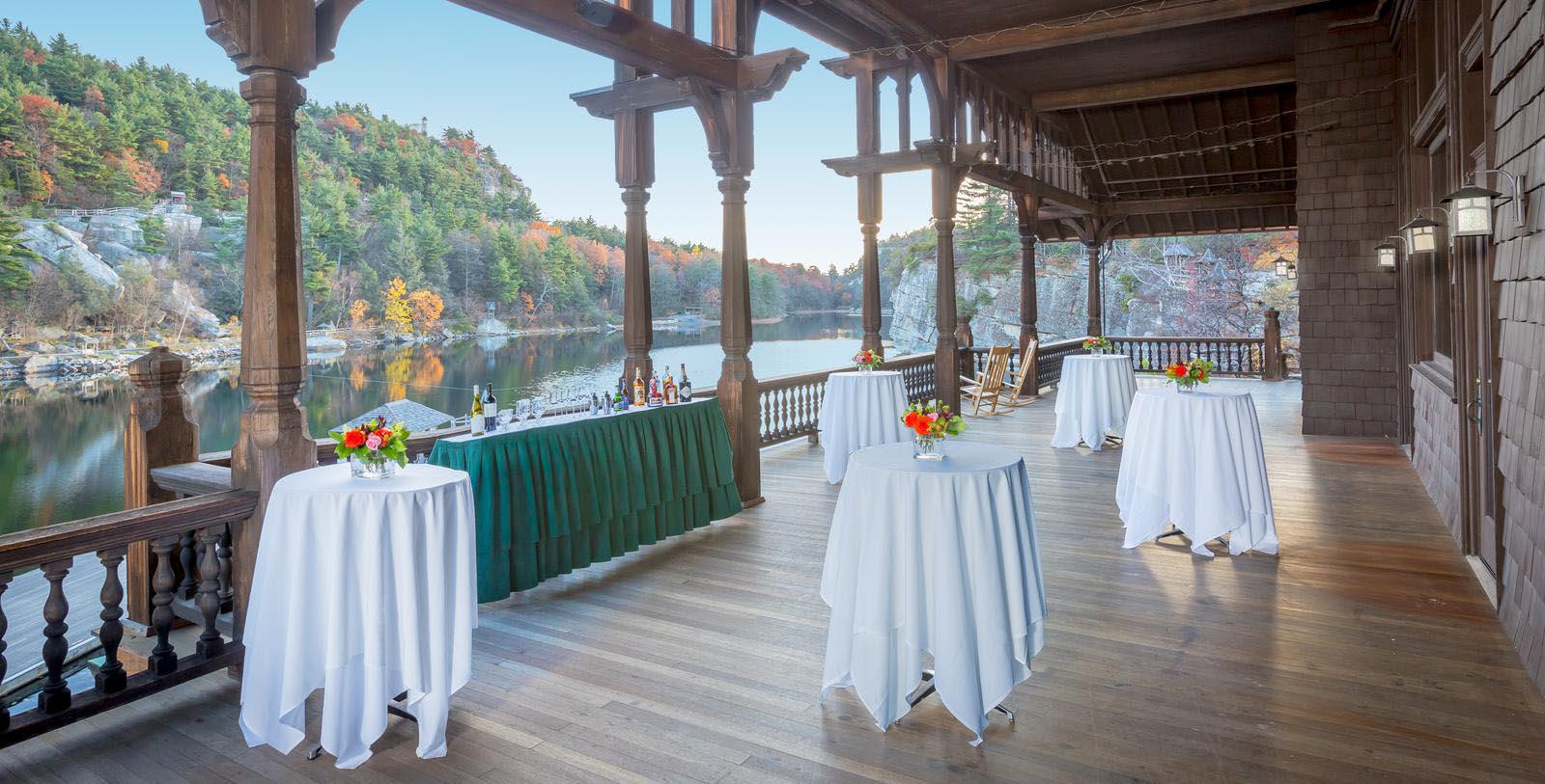 a covered patio with tables and drinks on the water