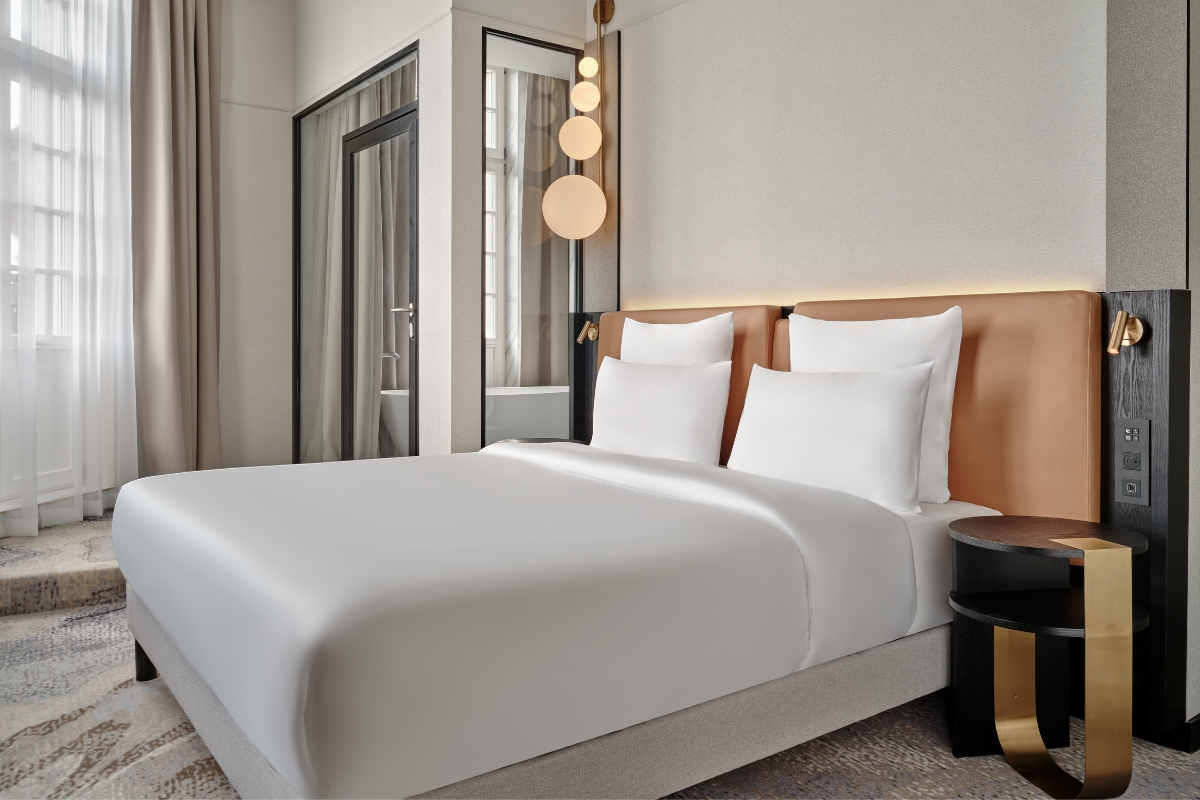 a bed with white sheets and pillows in a room
