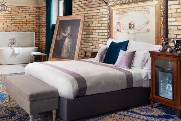 a bed with a bench and a painting on the wall