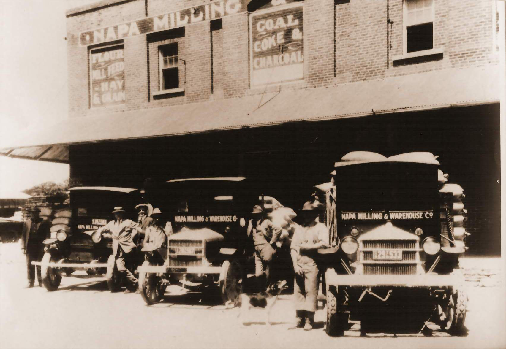 a group of men standing next to old trucks