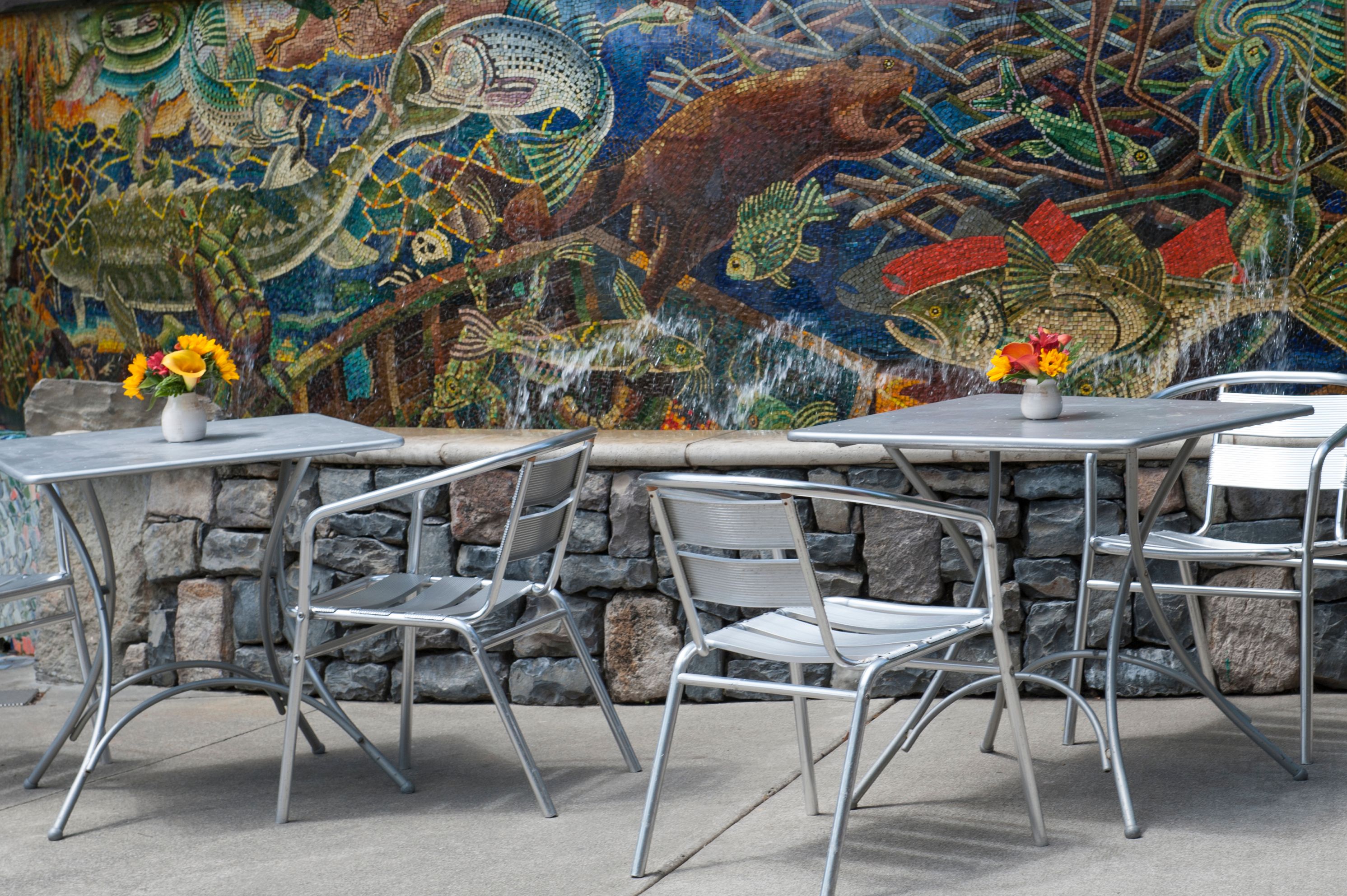 a table and chairs outside with a mosaic wall