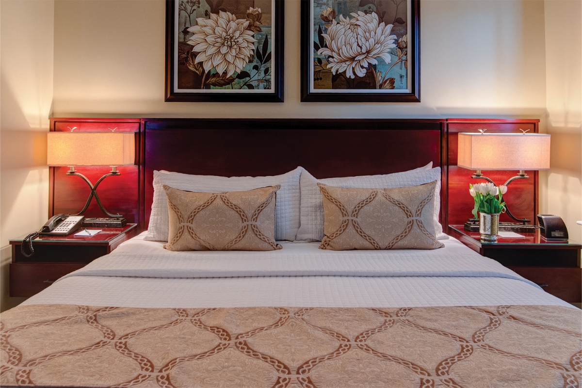 a bed with pillows and a lamp on the side of it
