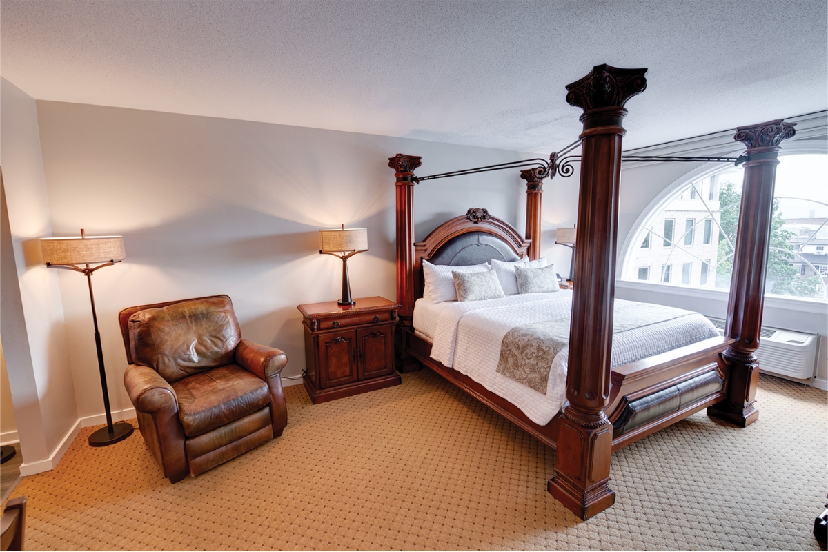 a bedroom with a four poster bed and a leather chair