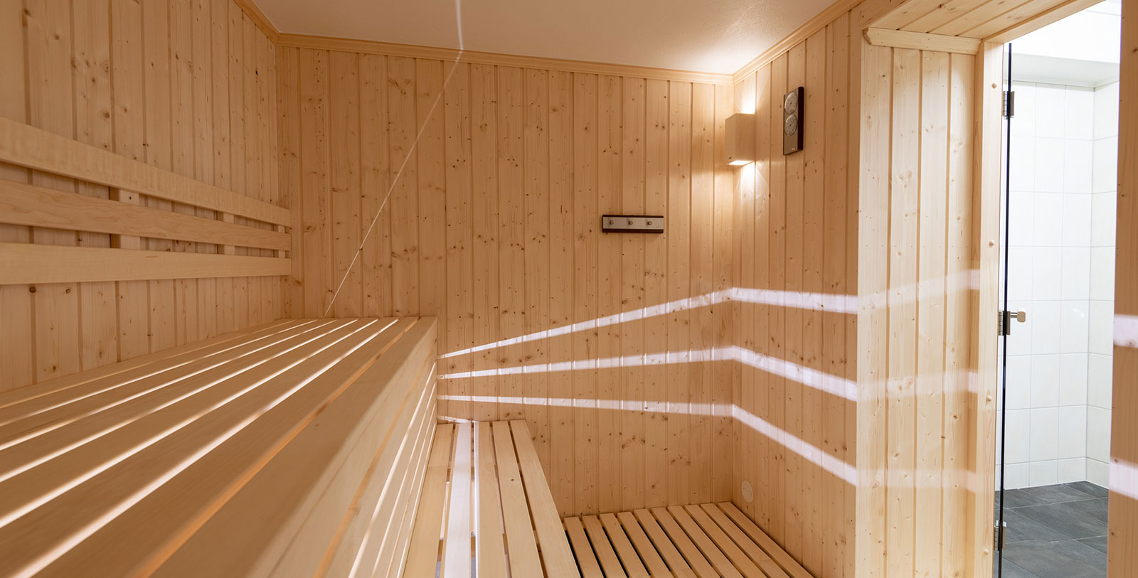a wooden sauna with light shining through the walls