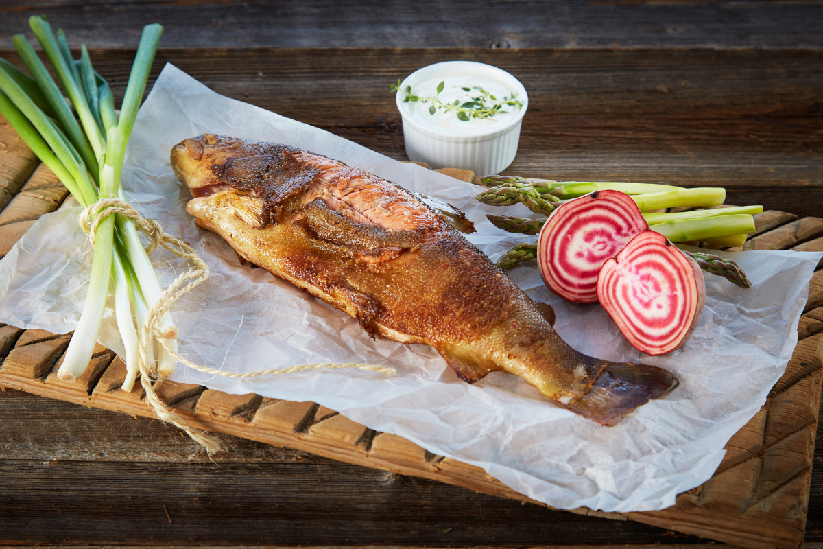 a fish on a cutting board with vegetables