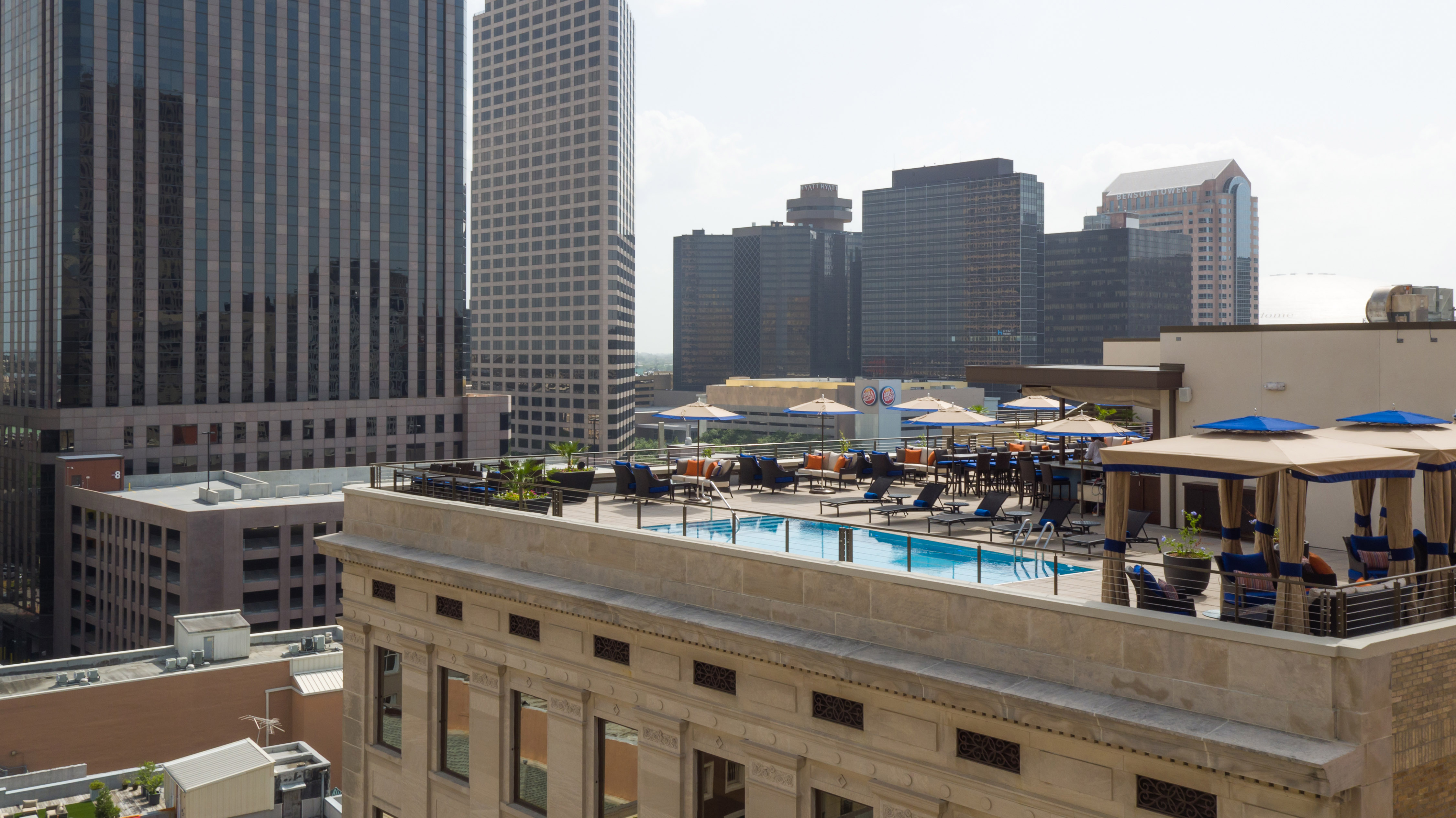 a rooftop pool with chairs and umbrellas in a city