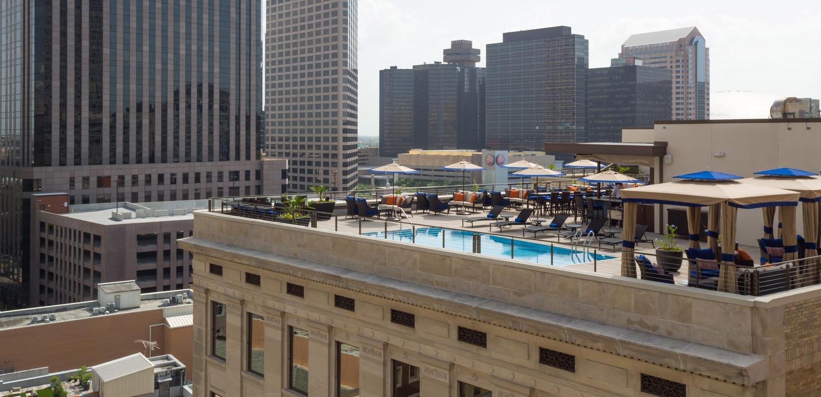 a rooftop pool with chairs and umbrellas