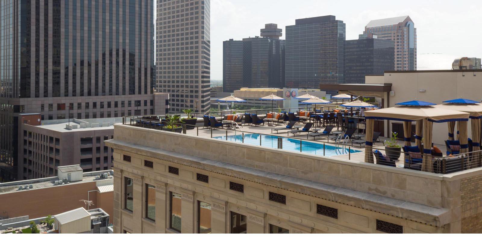 a rooftop pool with chairs and umbrellas