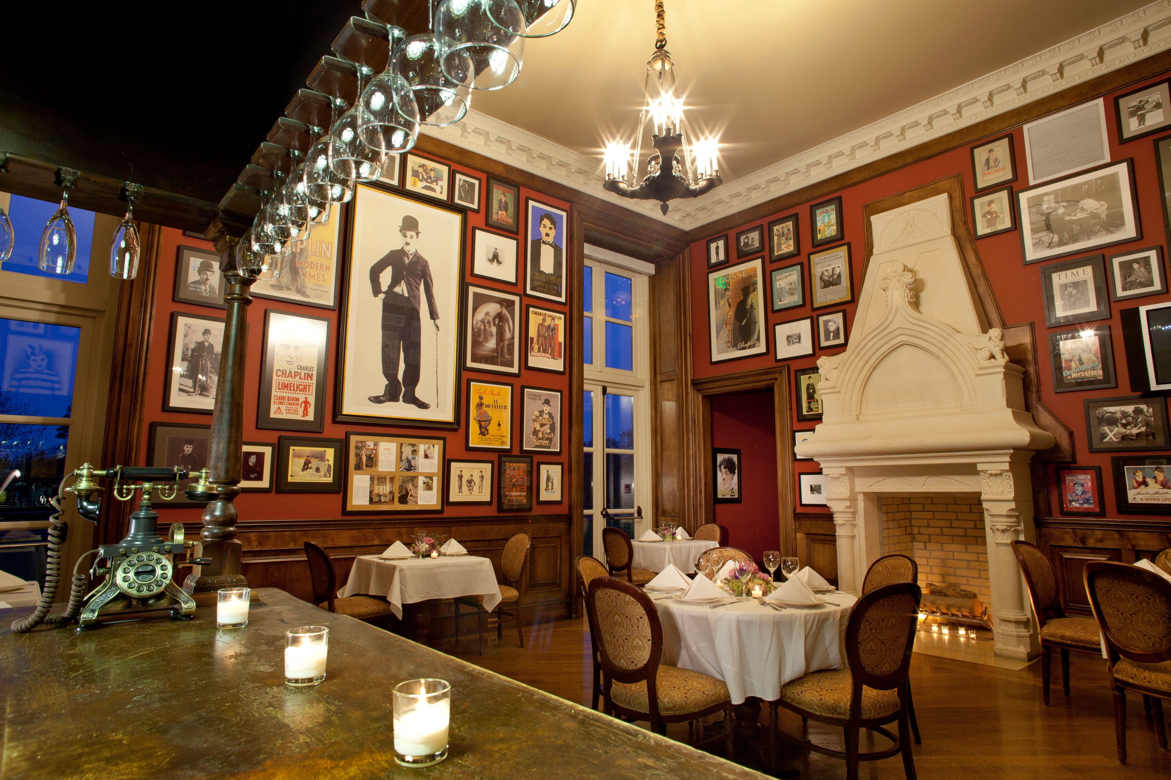 a room with a fireplace and tables and pictures on the wall