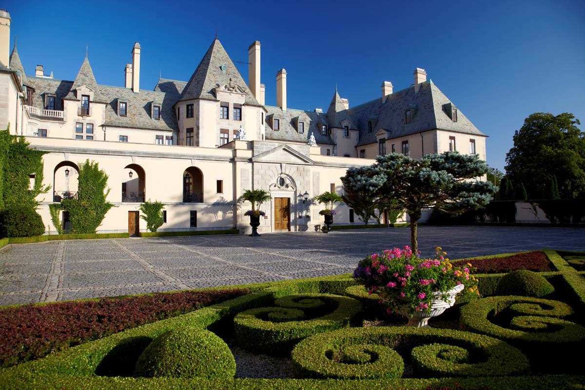 a large white building with a stone driveway and a garden