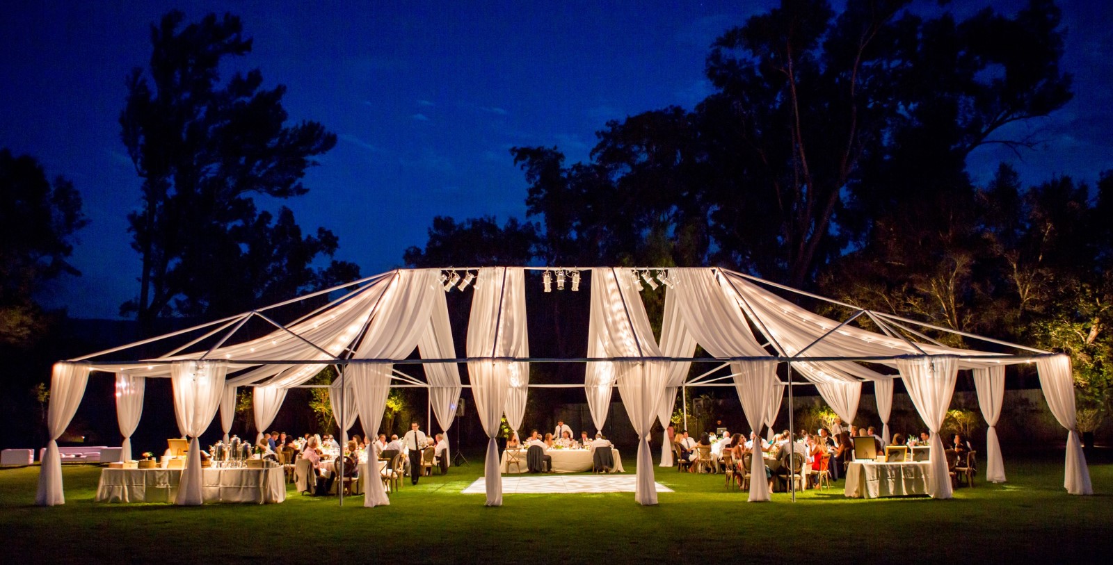 a group of people sitting at a table in a tent