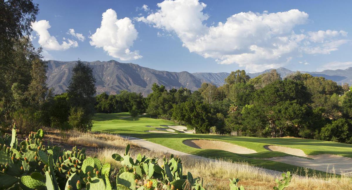 a golf course with cactus and mountains in the background