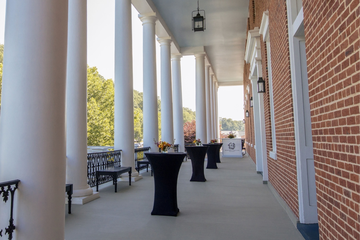 a long porch with white pillars and tables