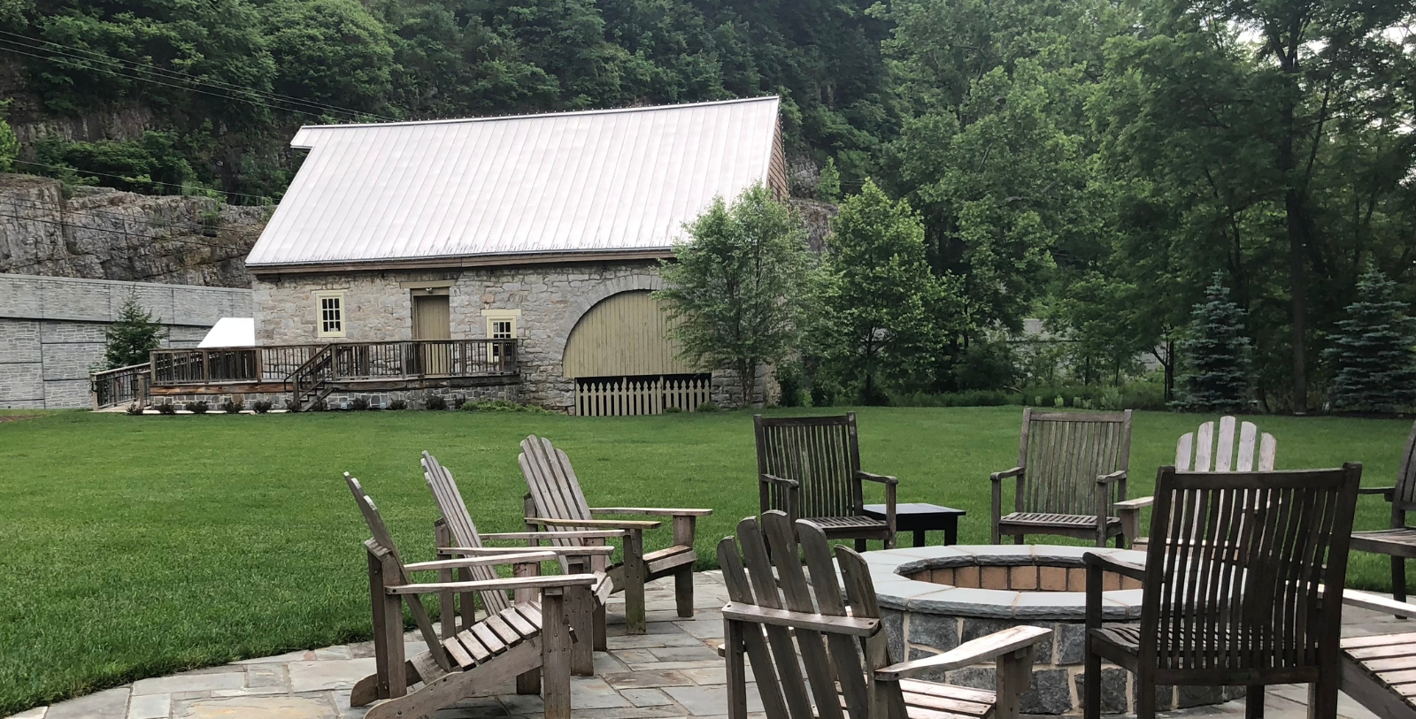 a patio with chairs and a fire pit in the back