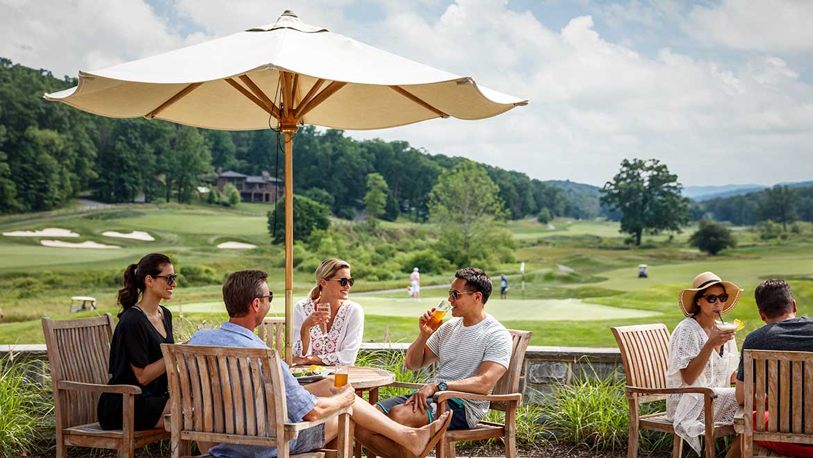 a group of people sitting at a table under an umbrella
