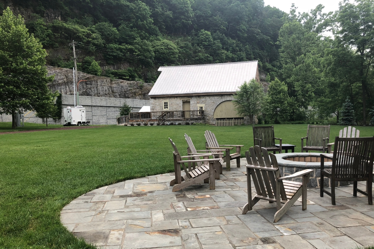 a patio with chairs and a fire pit in the middle of a grassy area