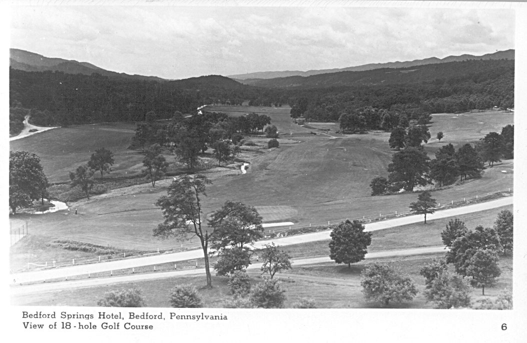a golf course with trees and a road