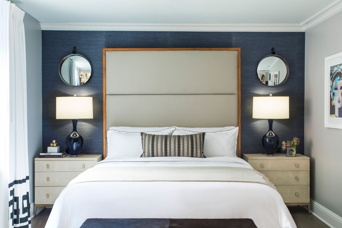 a bed with two lamps on the wall